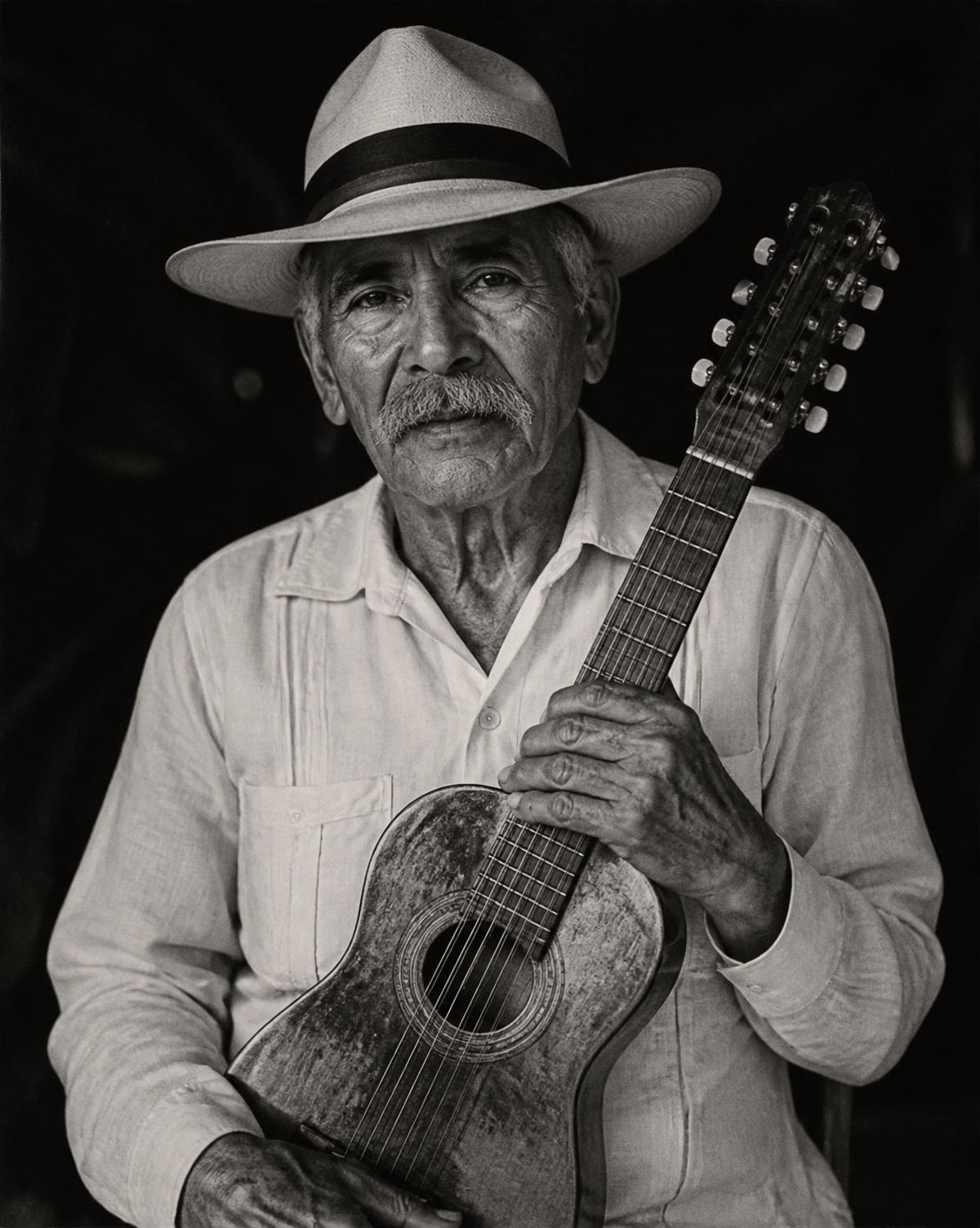 Retrato en blanco y negro de un músico tradicional con su instrumento de cuerda
