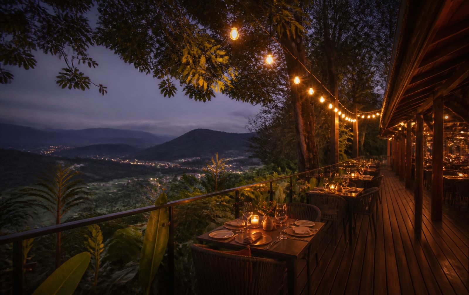 Terraza mirador de madera al atardecer con mesas iluminadas y vista al valle
