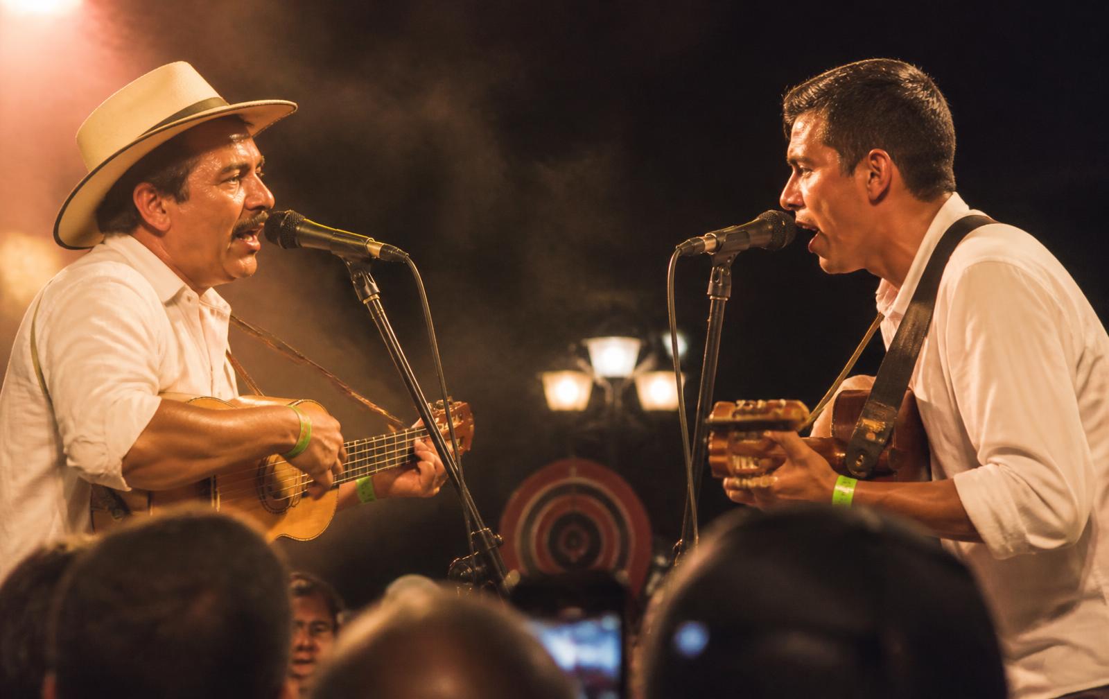 Dos trovadores improvisando frente a frente bajo luz dorada de escenario